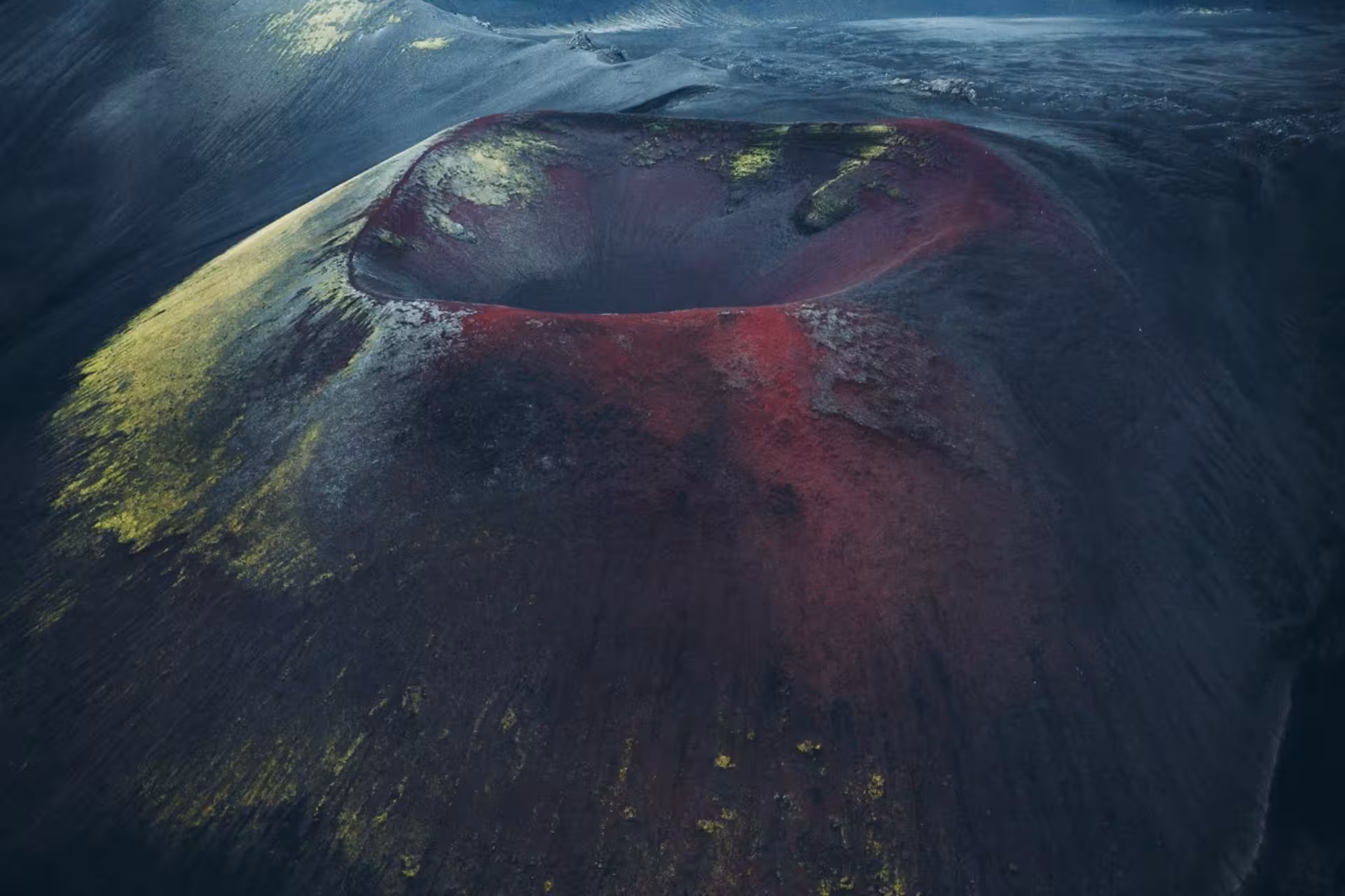 Aerial view of a red volcanic crater with black lava fields and green moss in Landmannalaugar Highlands Iceland