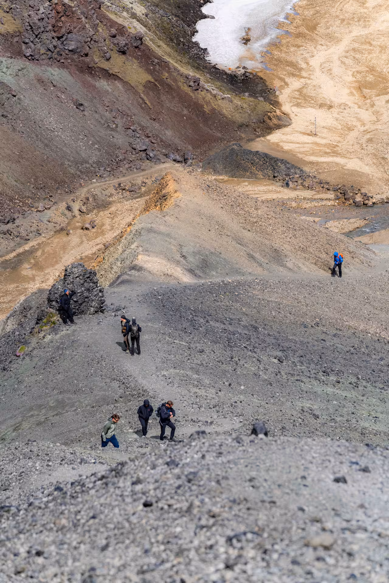 Hikers climbing steep volcanic terrain in Landmannalaugar Iceland with colorful rhyolite mountains in background