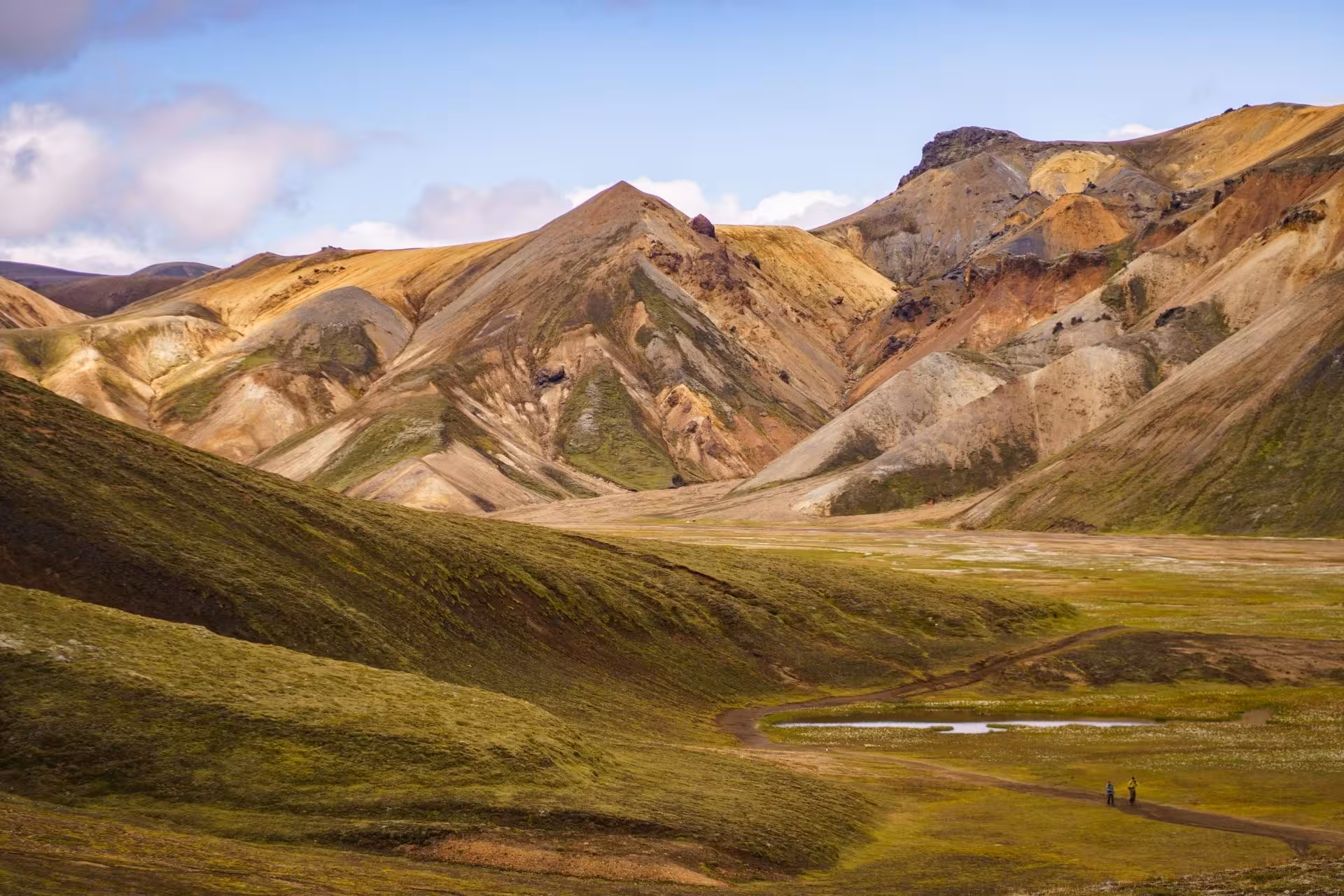 Colorful rhyolite mountains and green valley at Landmannalaugar Iceland Highlands with two hikers on trail