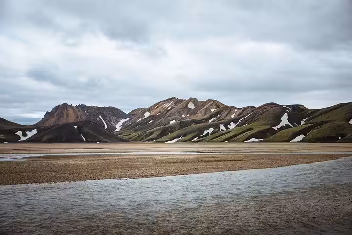 Landmannalaugar highland valley with colorful rhyolite mountains, snow patches, and glacial river in Iceland
