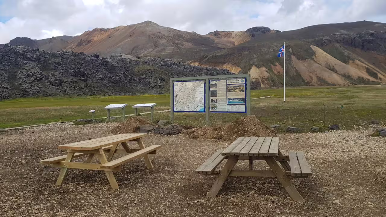 Picnic tables and informational trail map boards at Landmannalaugar highland area with colorful rhyolite mountains, Iceland
