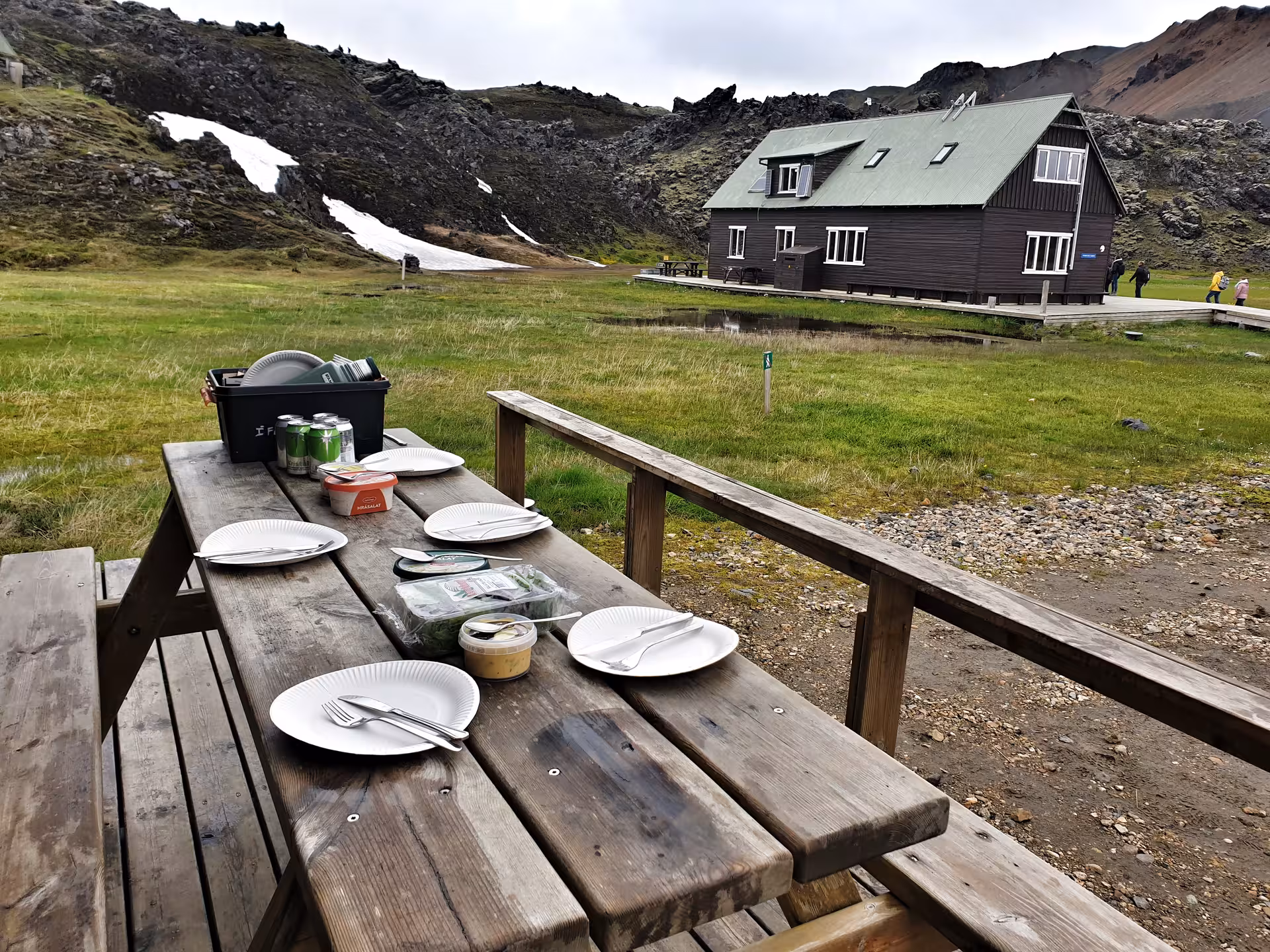 Picnic table set with plates and drinks near a mountain hut in Landmannalaugar, Iceland