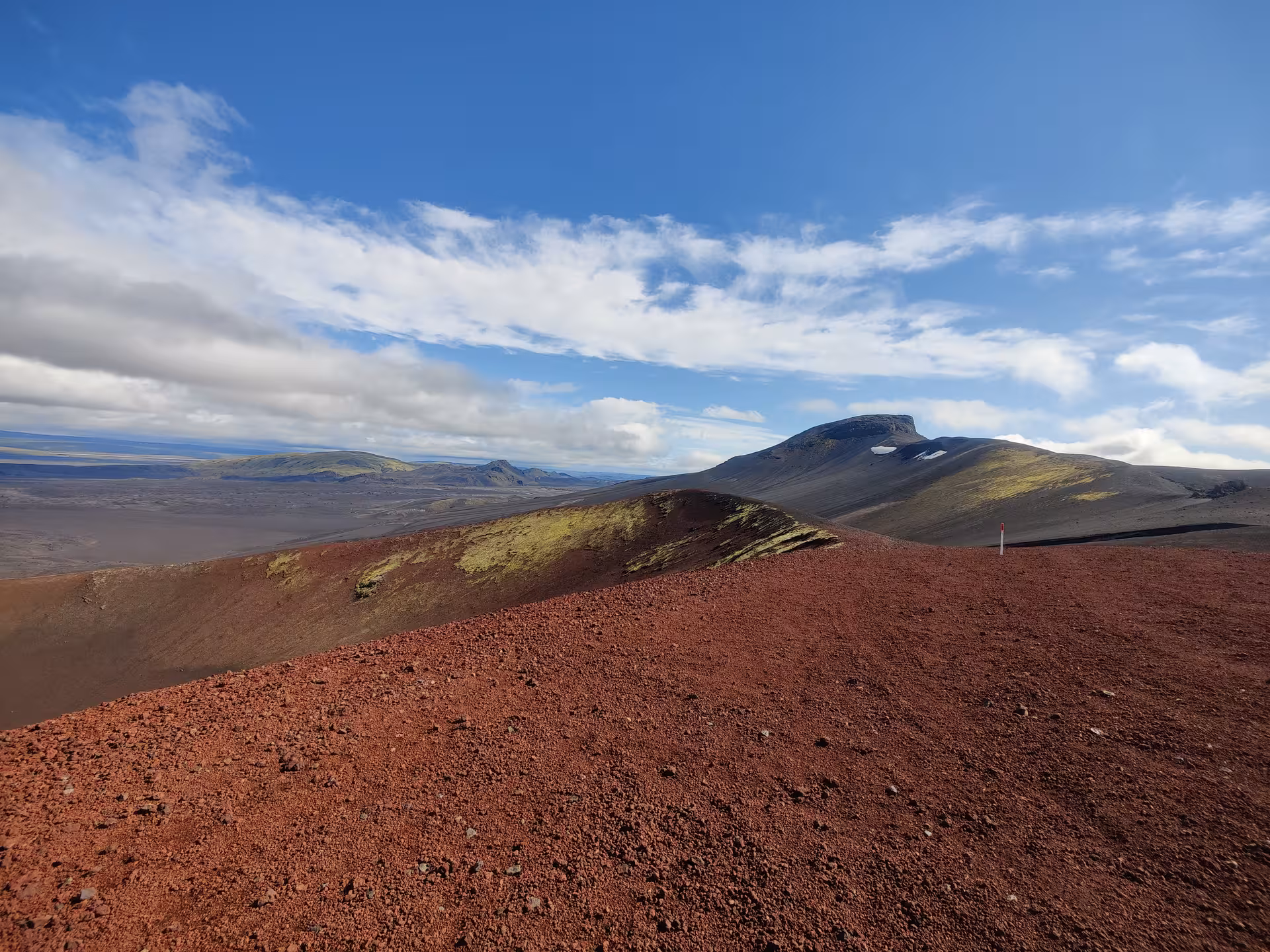 Red volcanic terrain and green moss-covered hills at Landmannalaugar highlands under blue sky