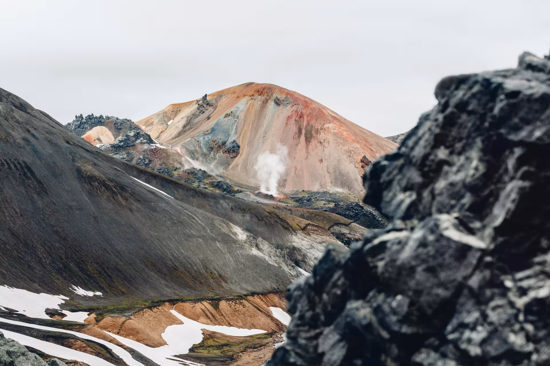 Colorful rhyolite mountains with geothermal steam vents and snow patches at Landmannalaugar, Iceland