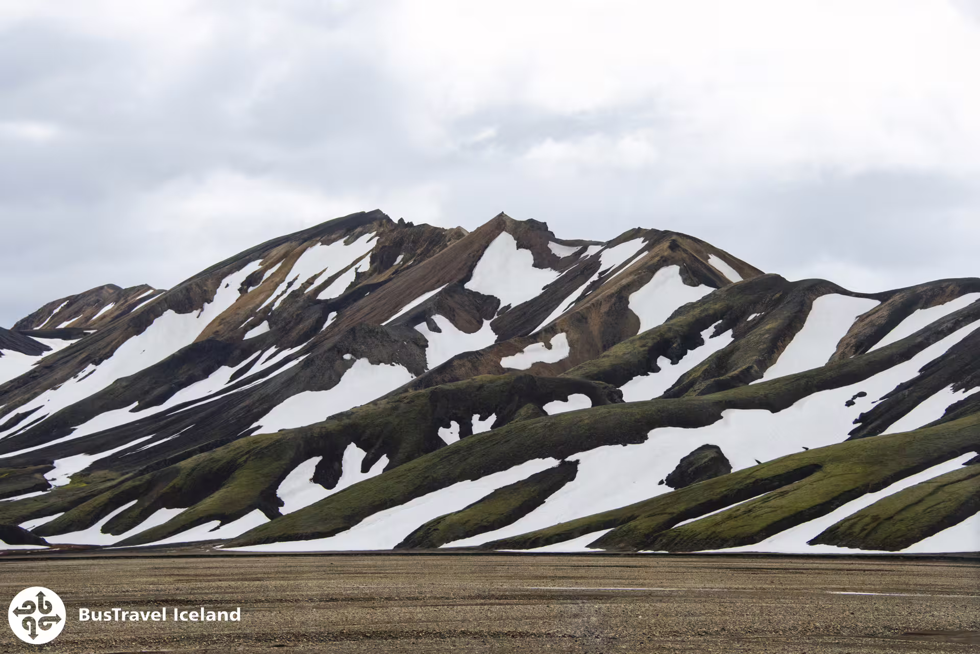 Snow-striped rhyolite mountains with green moss at Landmannalaugar, Iceland's highland region