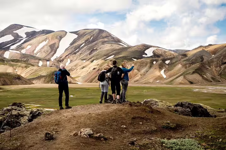 Hikers overlooking colorful rhyolite mountains and green valley at Landmannalaugar Iceland