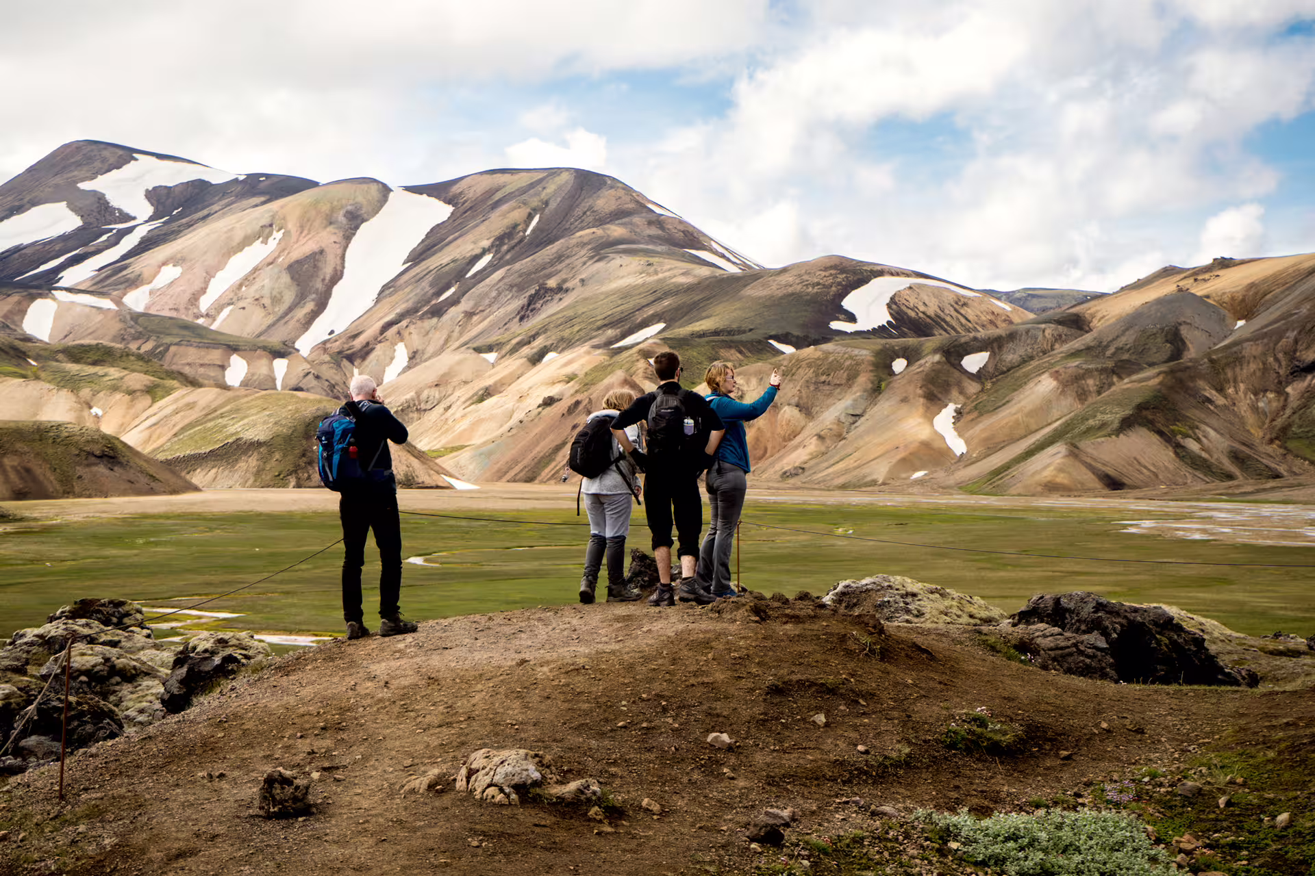 Hikers admiring colorful rhyolite mountains and green valley at Landmannalaugar, Iceland