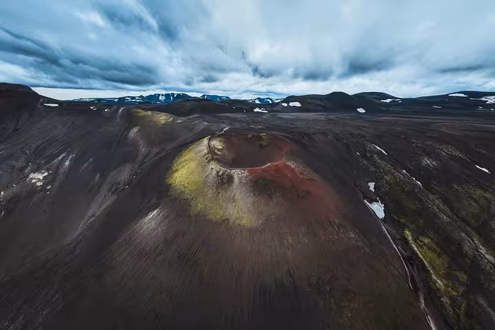 Aerial view of a colorful volcanic crater with red and green hues in Iceland Highlands