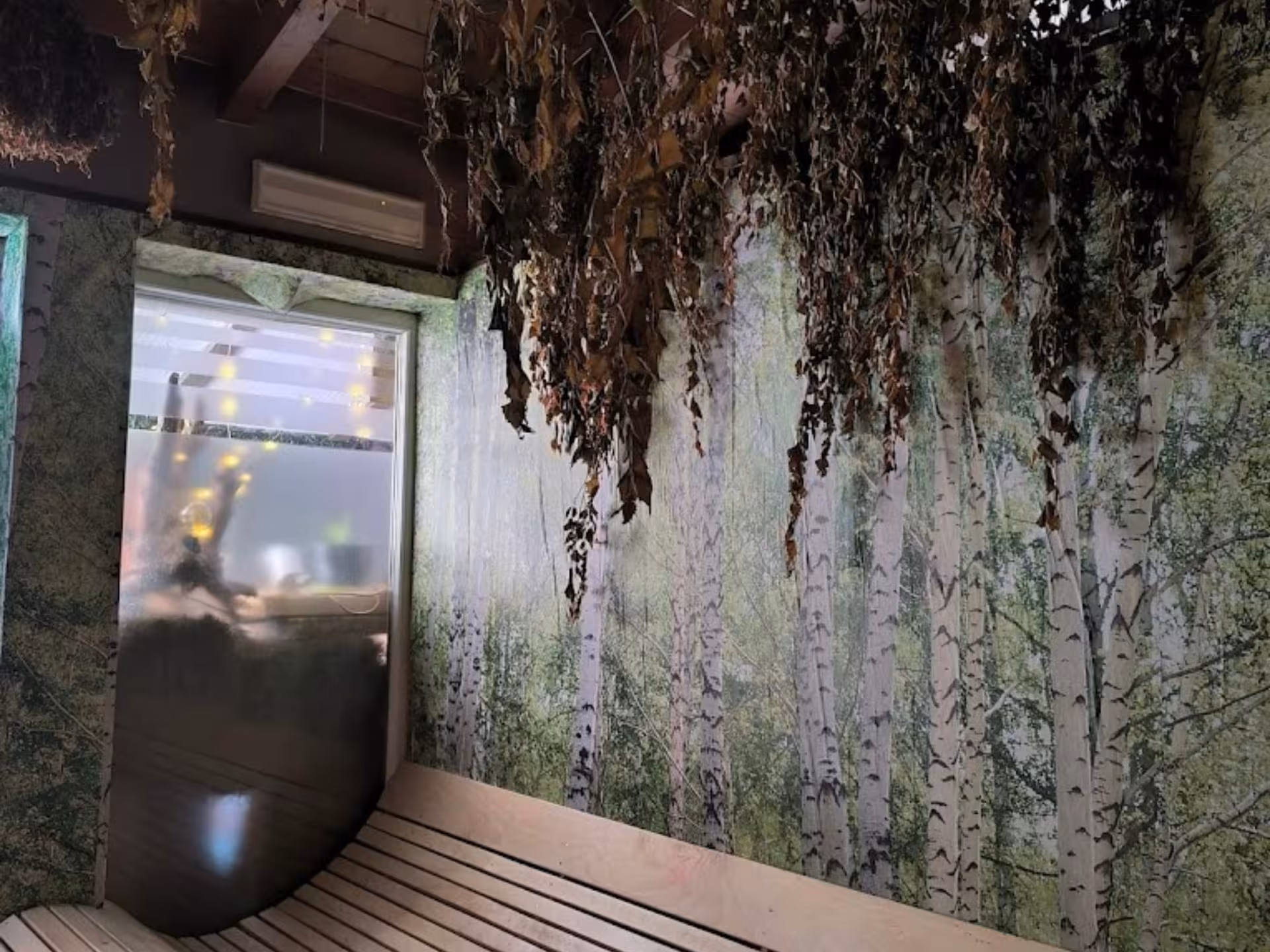Cozy sauna room with birch tree decor and dried herbs, offering a tranquil experience at Langhe Spa Wellness.
