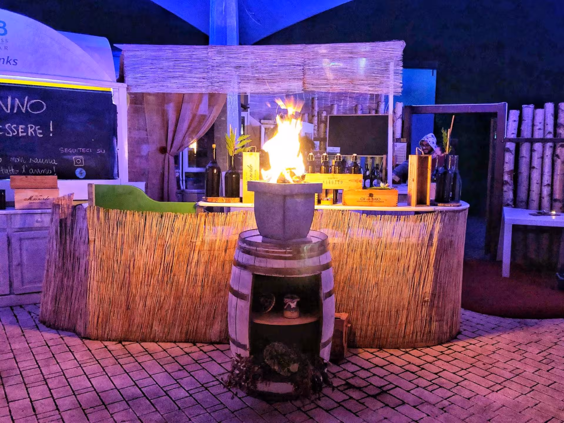 Inviting Langhe spa bar with warm fire pit, wine bottles, and rustic decor for a relaxing experience.