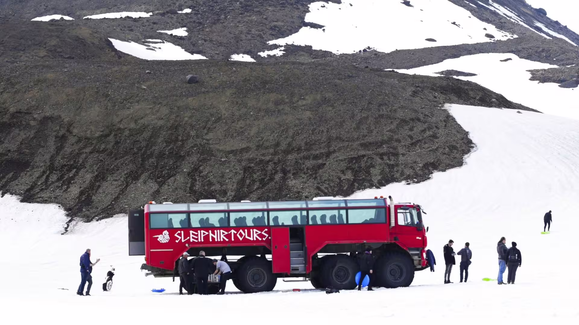 Red glacier bus with guests on Langjökull snowfield during Summer Solstice tour from Gullfoss, Iceland