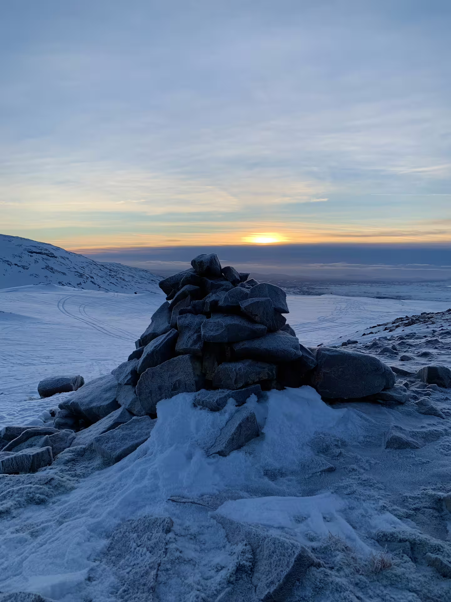 Stone cairn on snowy Langjokull glacier summit at sunset, Iceland winter landscape
