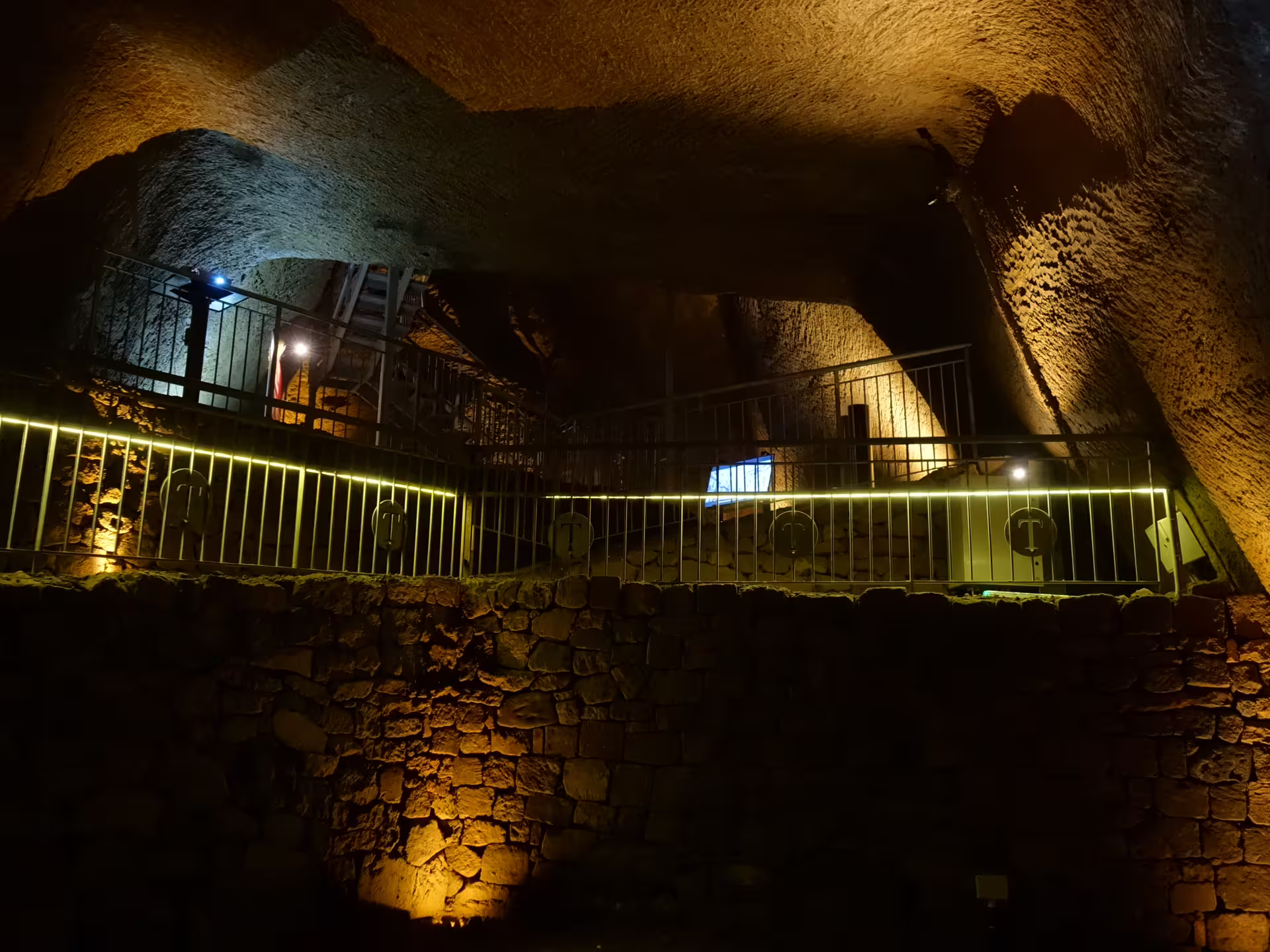 Passerella moderna illuminata nel Lapis Museum di Napoli, all’interno delle antiche cavità del Decumano Sommerso