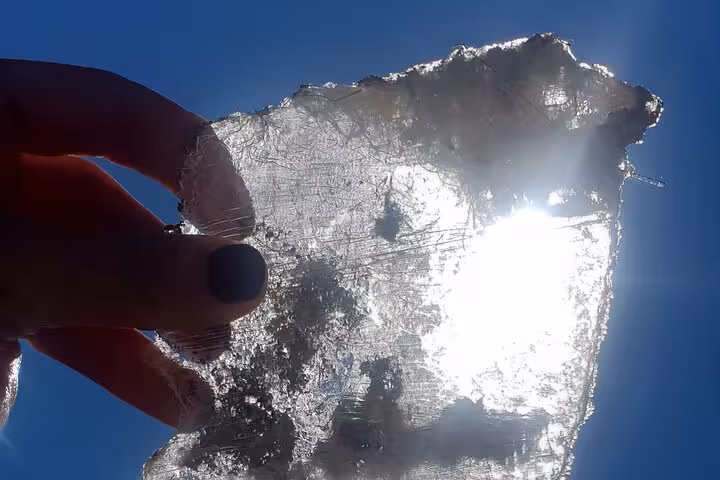 Hand holding translucent lapis specularis crystal sheet against sun, Roman mine tour in Cuenca, Spain
