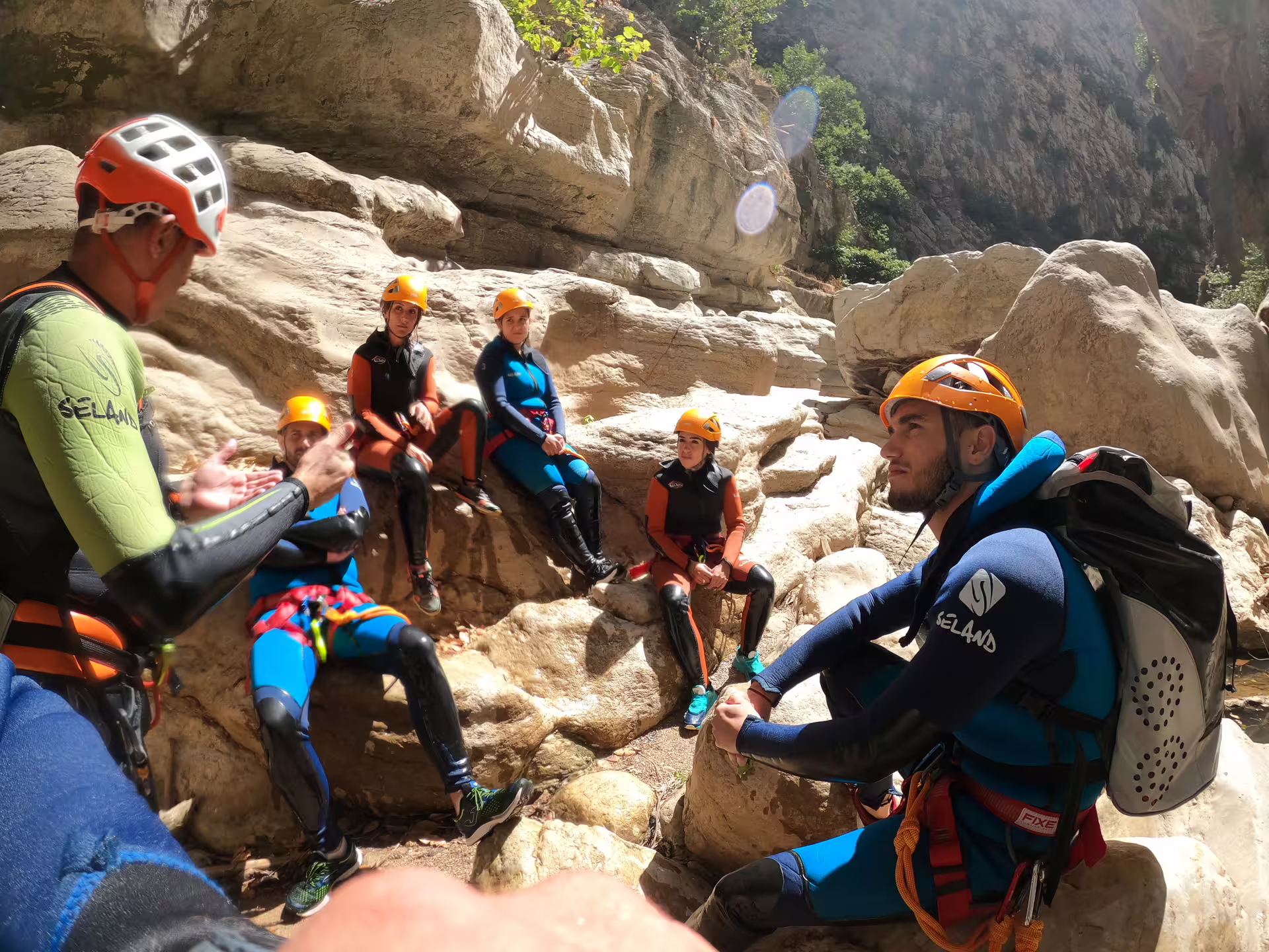 A guide in wetsuit and helmet briefs a group of canyoners on rocky terrain at Las Buitreras Canyon Málaga