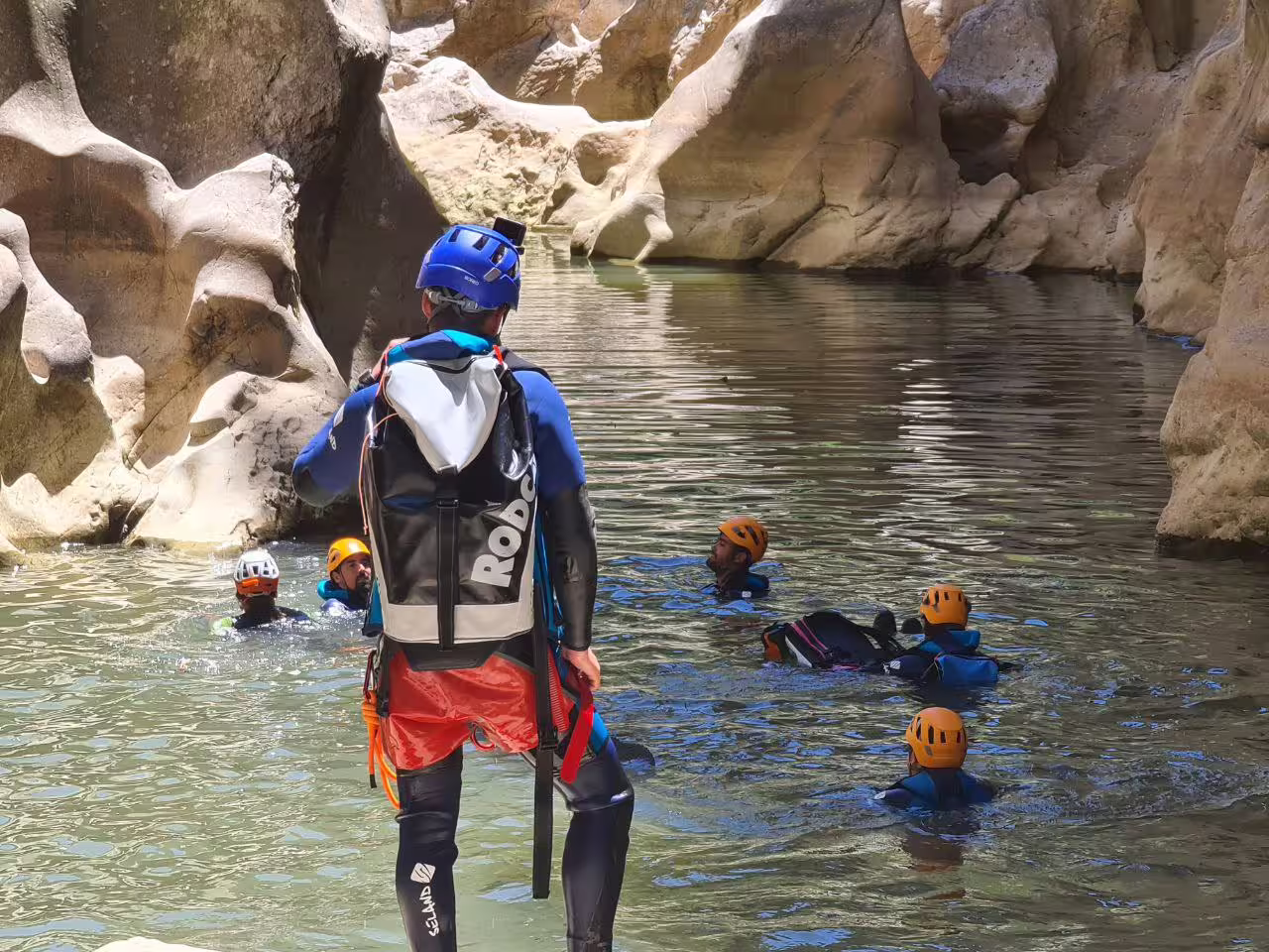 Canyoning guide supervising group swimming in Las Buitreras Canyon scenic rock pools Málaga Province