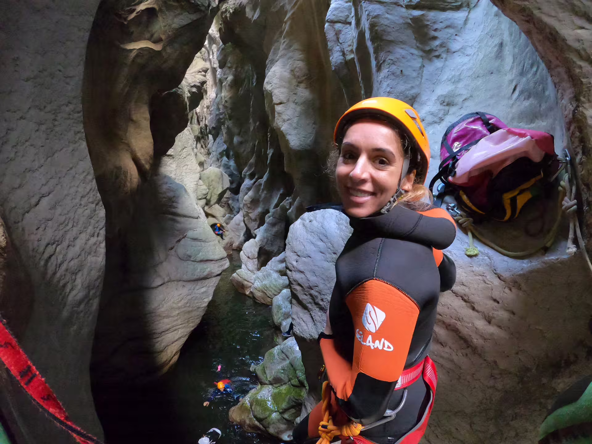 Smiling woman in wetsuit and helmet canyoning through narrow Las Buitreras gorge in Málaga Province Spain