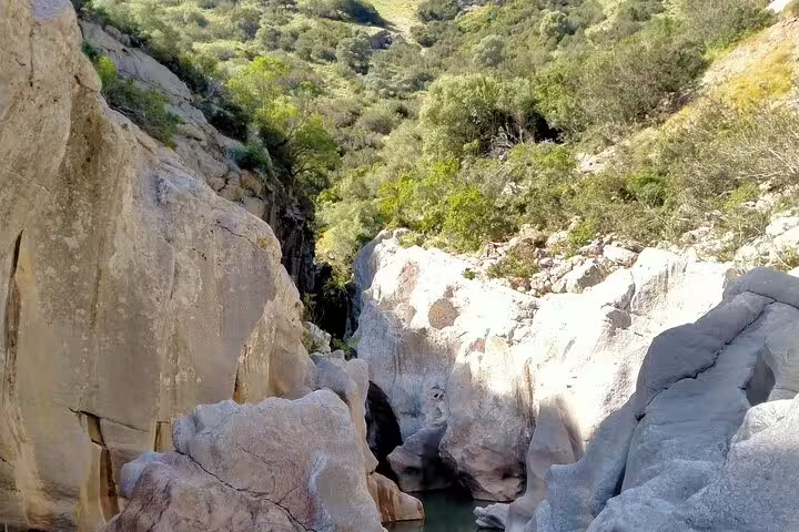 Stunning natural rock formations and emerald pool inside Las Buitreras Canyon guided tour in Málaga Province