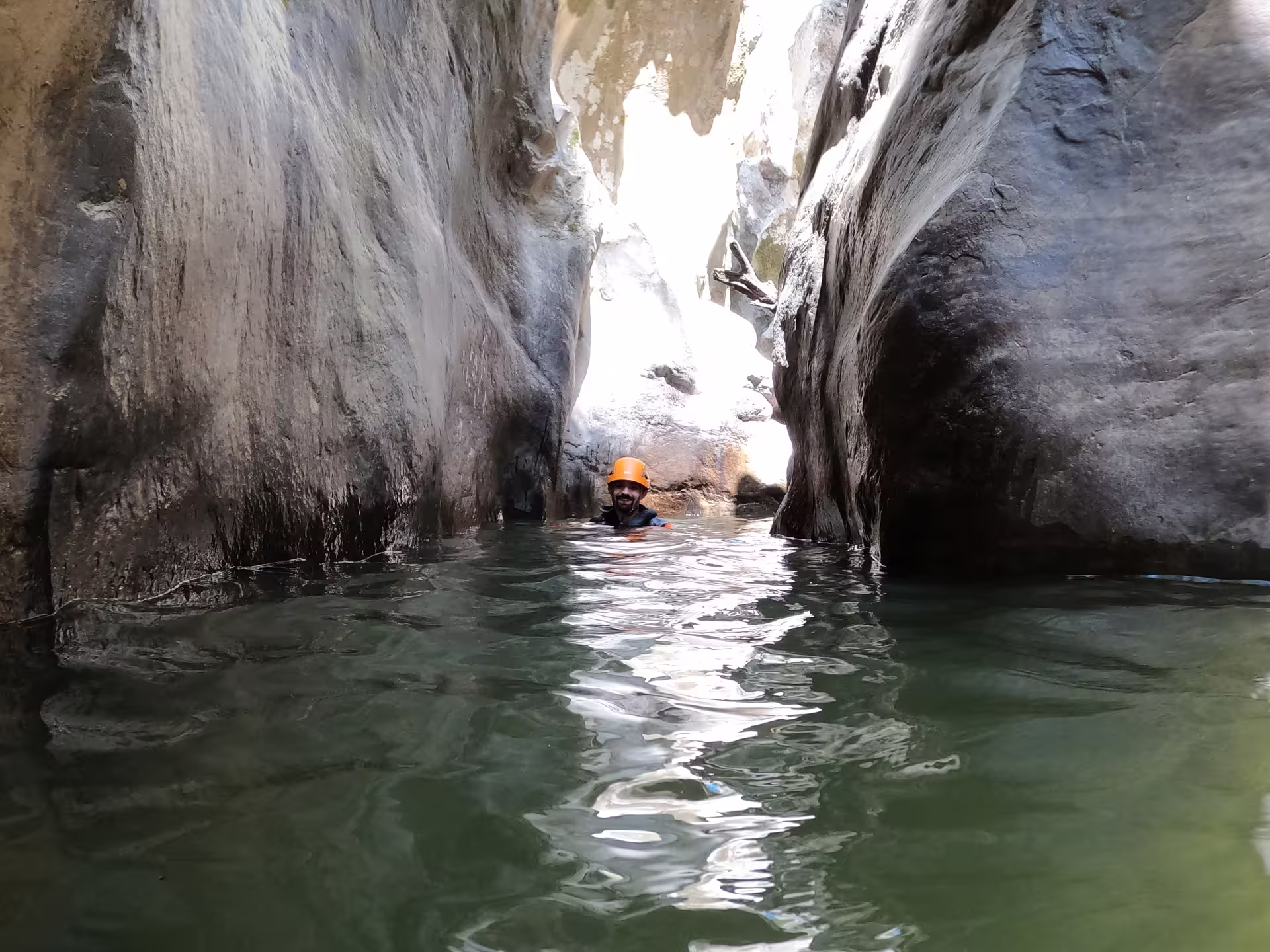 A helmeted adventurer swims through the narrow water-filled gorge of Las Buitreras Canyon on a guided tour in Málaga.