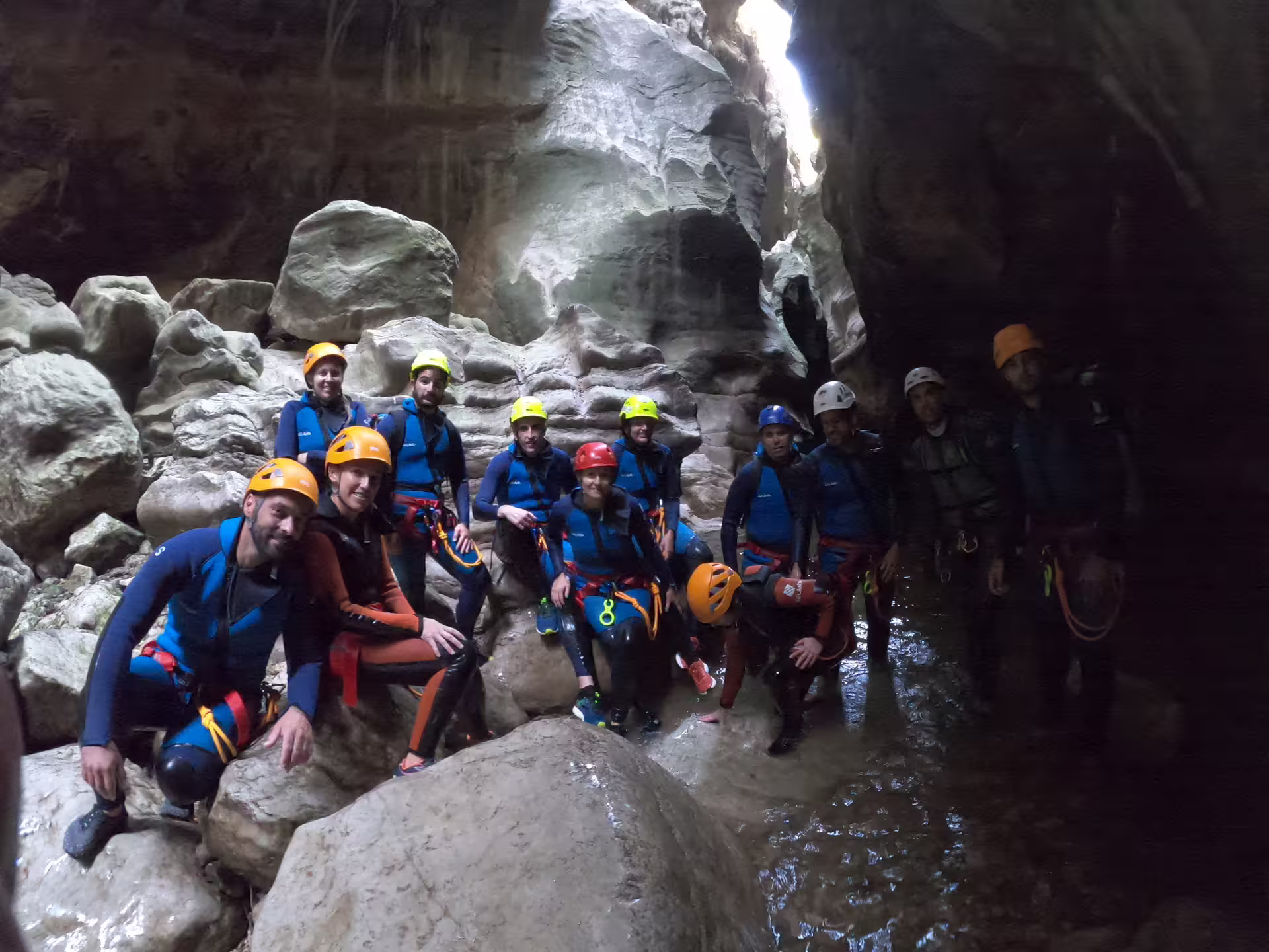 Adventure tour group with helmets and harnesses resting on rocks inside Las Buitreras Canyon Málaga Province