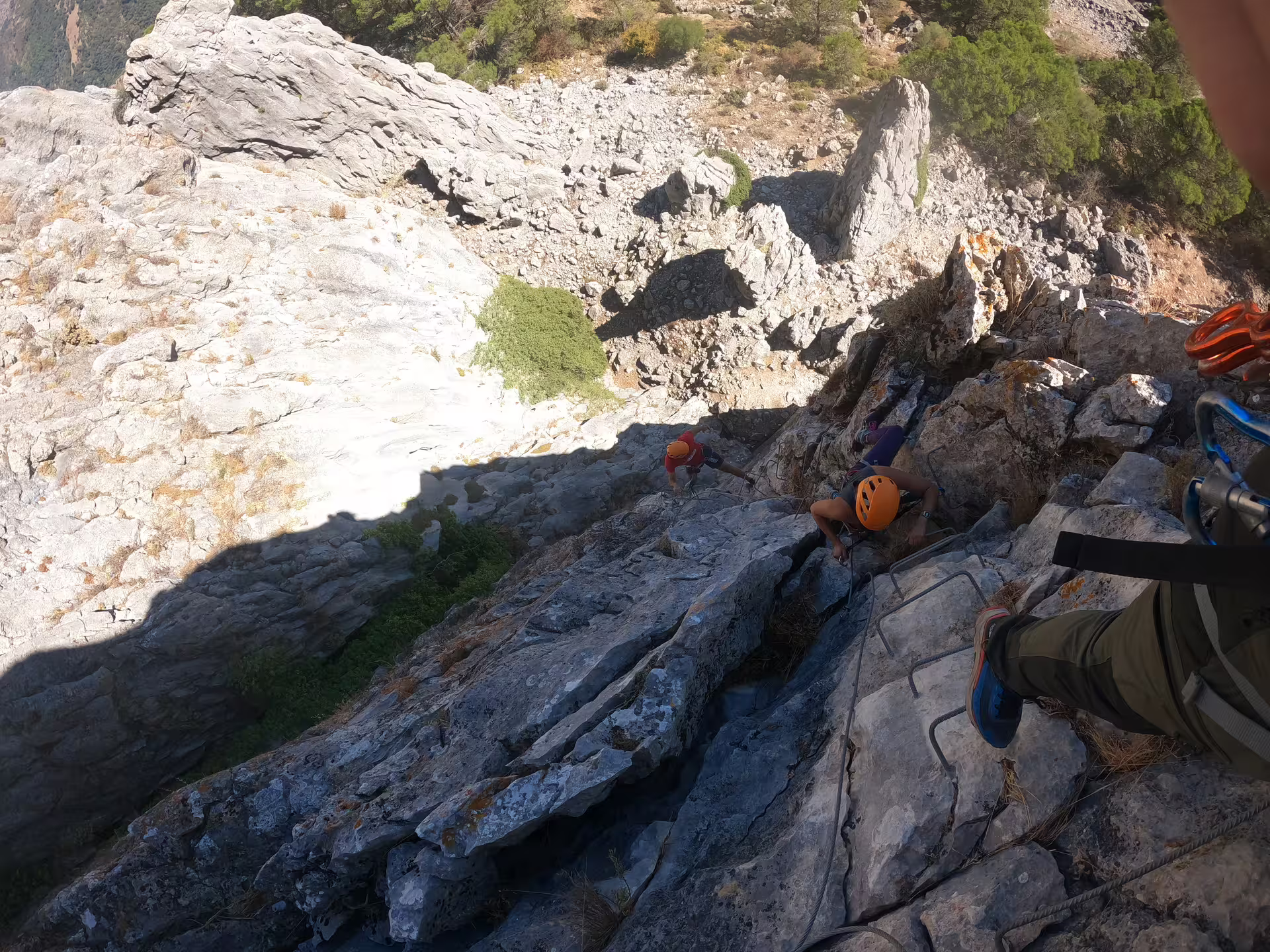 Guided rock climbing group wearing helmets scaling steep cliffs at Las Buitreras Canyon Málaga adventure tour