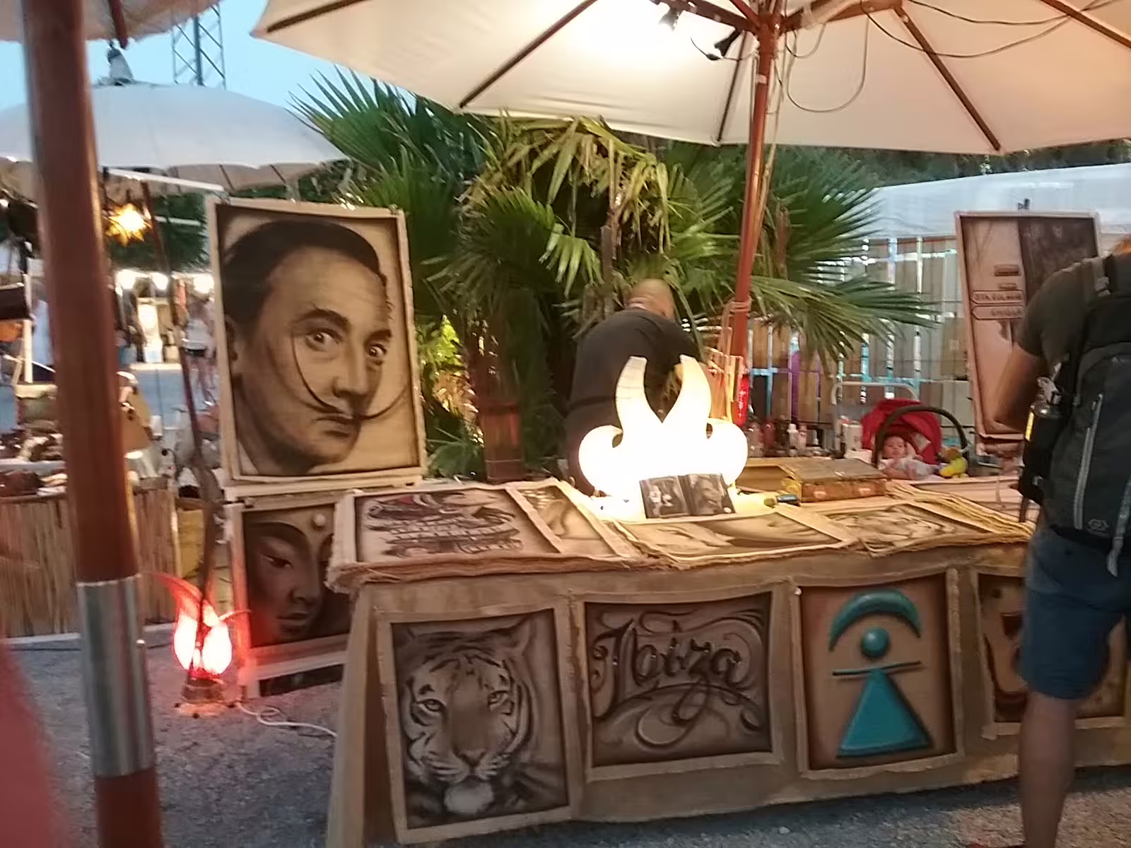 Las Dalias hippie market art stall at dusk on Ibiza sunset tour by bus, featuring handmade prints and crafts