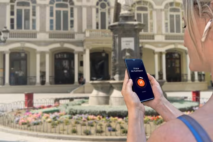 Tourist holding smartphone with audio tour app at Place de Cairasco fountain in Las Palmas