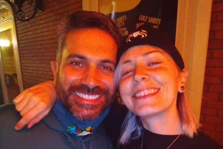 Two smiling people posing together outdoors near a brick wall during a Las Vegas walking tour