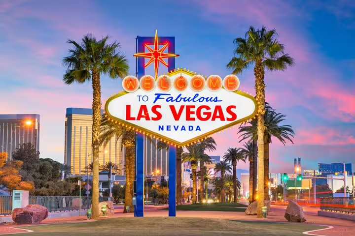 Welcome to Fabulous Las Vegas Nevada neon sign illuminated at dusk with palm trees and Strip skyline