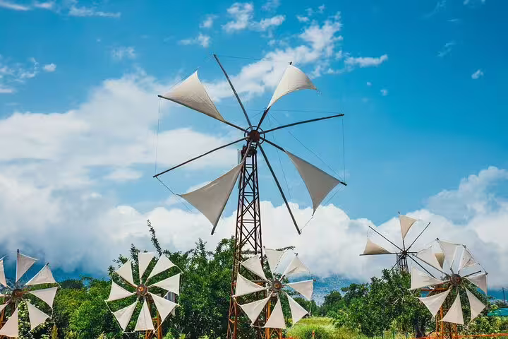 Traditional windmills spinning on the Lasithi Plateau under a bright blue sky, part of the Zeus Cave private tour.