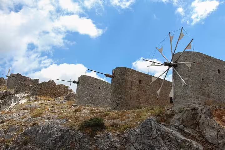 Historic stone windmills on the rocky hills of Lasithi Plateau under a bright blue sky, Crete.