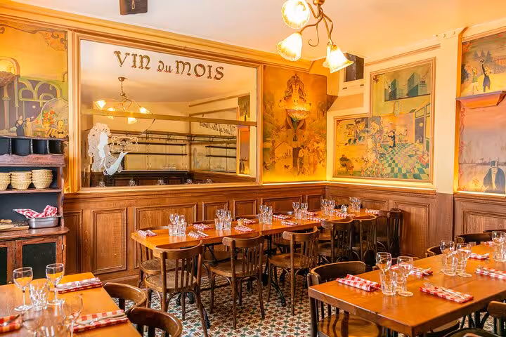 Cozy Parisian bistro dining room with wooden chairs, red checkered napkins, and Vin du Mois mirror sign