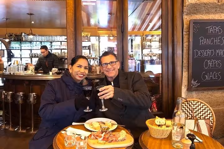 Couple toasting wine glasses over tapas and charcuterie board at a Paris bistro in the Latin Quarter