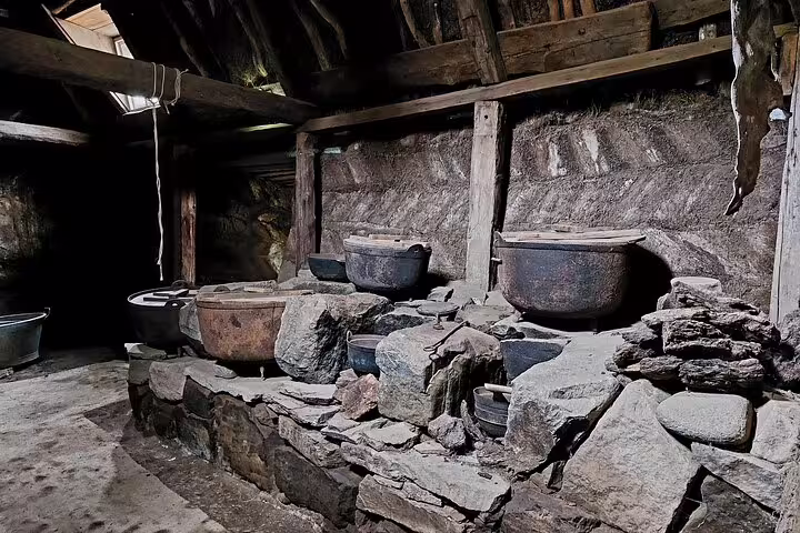 Ancient stone hearth with large cast iron cauldrons inside historic Laufas turf farmhouse, North Iceland