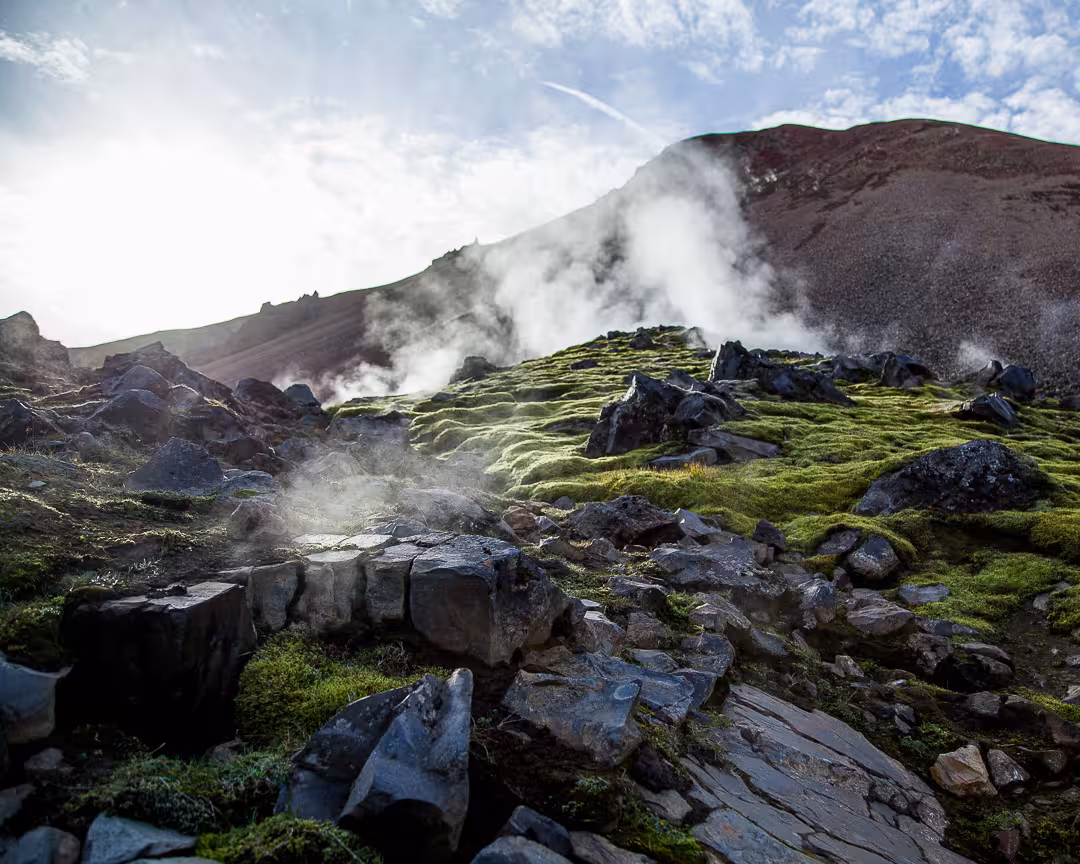 Geothermal steam rising from mossy volcanic rocks on Laugavegur trail Iceland