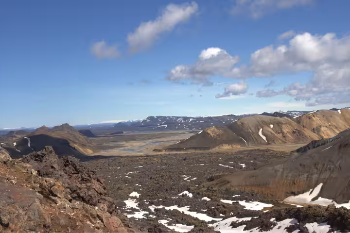 Panoramic view of volcanic lava fields and snow-dusted mountains along the Laugavegur Trek in Iceland