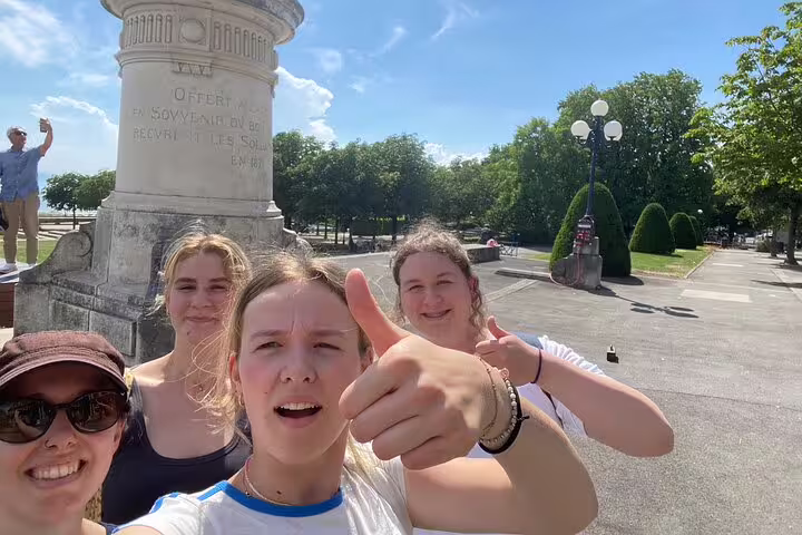 Group selfie by a monument in Lausanne city center, celebrating clues on a self-guided scavenger hunt