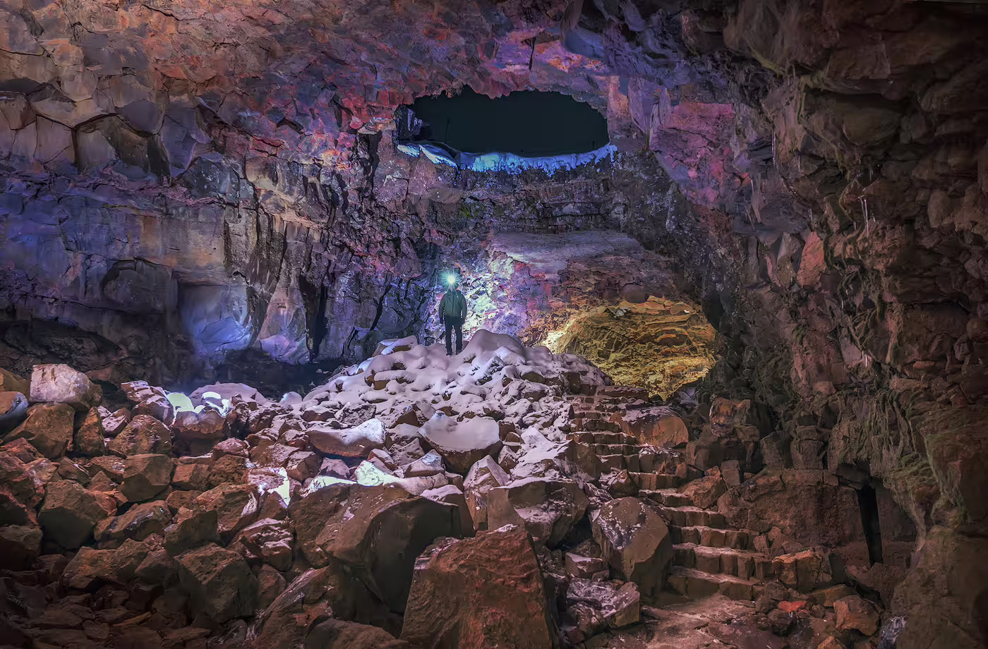 Adventurer explores a stunning, illuminated lava cave with rocky terrain, part of the thrilling Lava & Air Adventure Combo tour.
