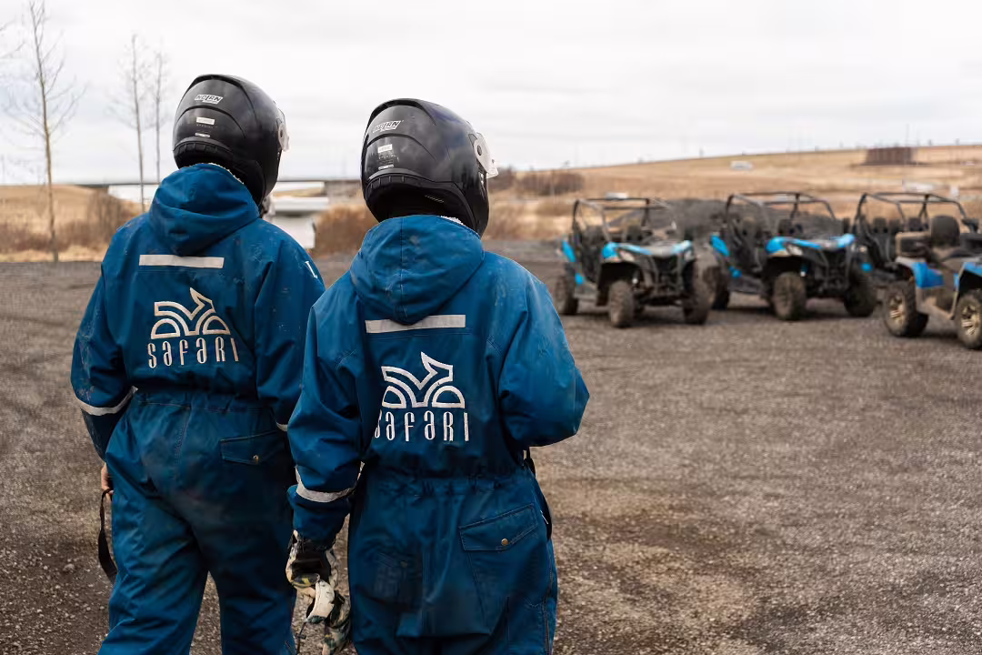 Adventurers in blue suits and helmets prepare for a thrilling 2-hour buggy ride across rugged lava fields.
