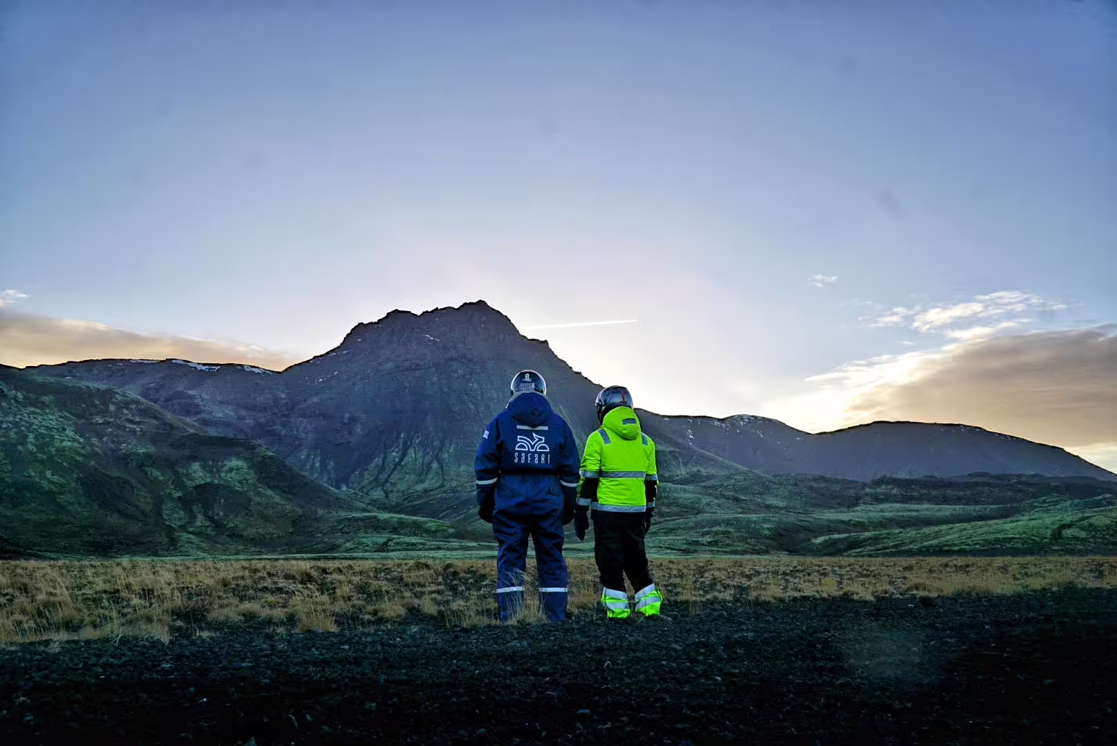 Two adventurers in safety gear admire a stunning volcanic landscape during a 2-hour lava field buggy tour at sunrise.