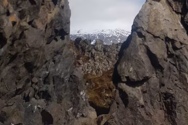 Rocky lava formations framing a snow-capped Snæfellsjökull glacier on Snaefellsnes Peninsula, Iceland