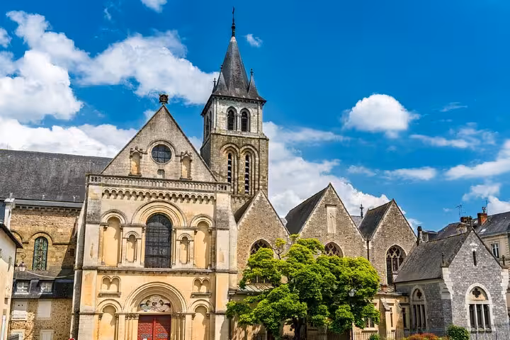 Historic Romanesque church with bell tower in Laval, France, under a bright blue sky