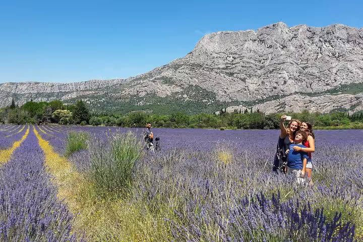 Tourists taking a selfie in a lavender field with rocky mountain backdrop in Provence, French Riviera