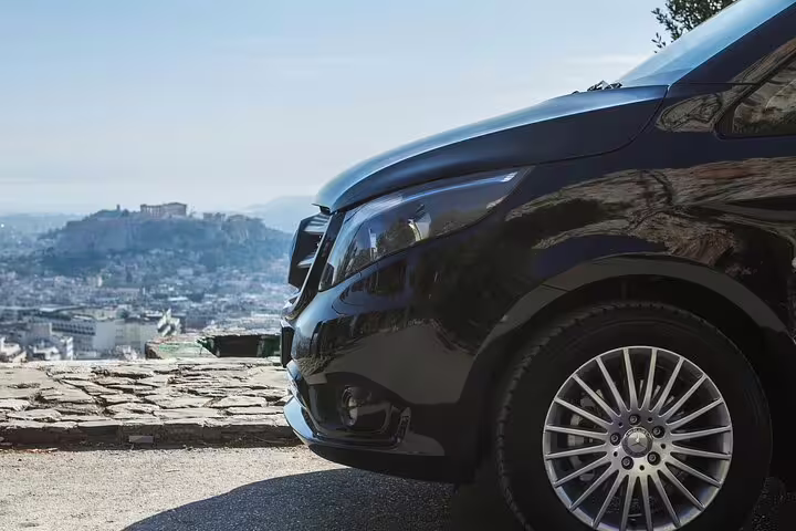 Black luxury van ready for Lavrio port to Athens hotels private arrival transfer, smooth ride with scenic backdrop