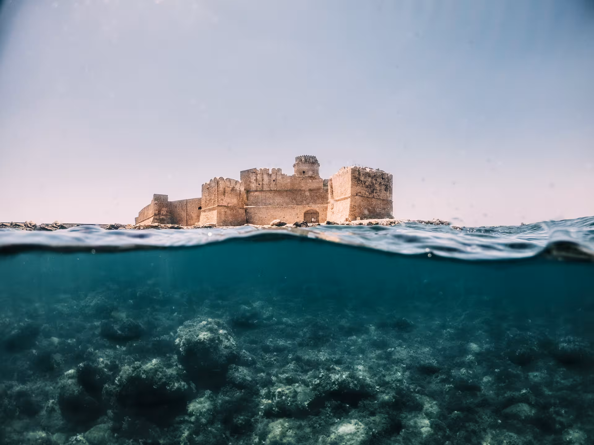 View of Le Castella's historic fortress above vibrant marine life, seen from Capo Rizzuto's crystal-clear waters.