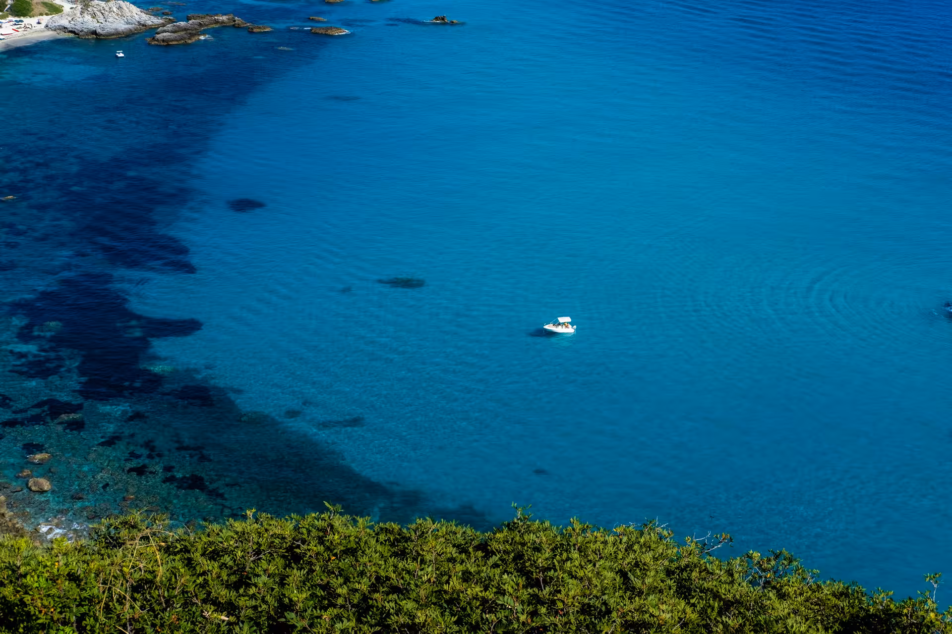 Overhead shot of a solitary boat in the vibrant blue waters of the Capo Rizzuto marine area, perfect for seabed exploration.