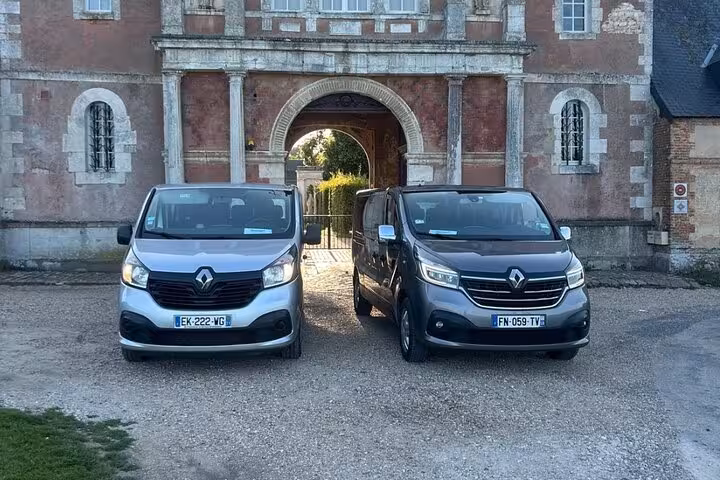Two Renault Trafic vans parked in front of a historic French château gateway