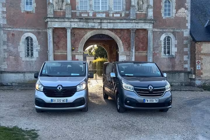 Two Renault Trafic vans parked in front of a historic French château gateway in Normandy