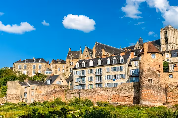 Historic Le Mans old town buildings and ancient Roman walls under a bright blue sky, France