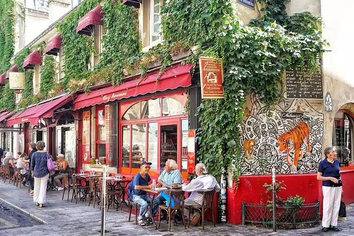 Charming Parisian café terrace in Le Marais with ivy-covered walls, red awnings, and outdoor seating